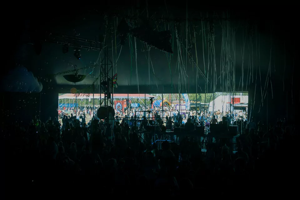Festival tent interior with a silhouetted crowd and a bright opening