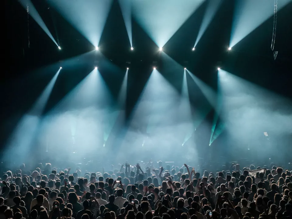Concert crowd beneath sweeping blue spotlights