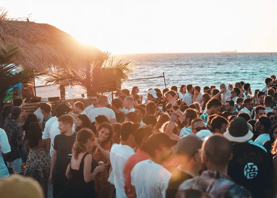 Beach party crowd beside the sea at sunset